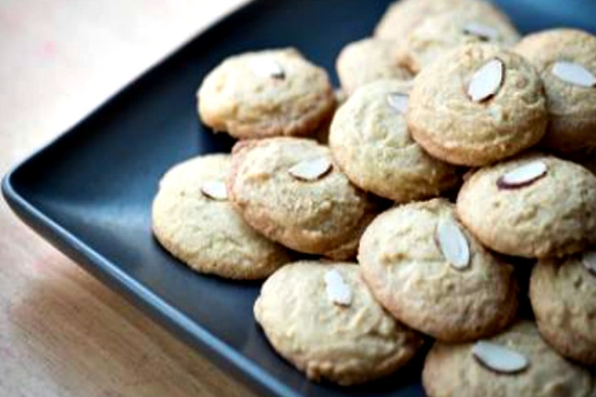 Blue plate piled Sephardic macaroons each topped with a sliver of almond